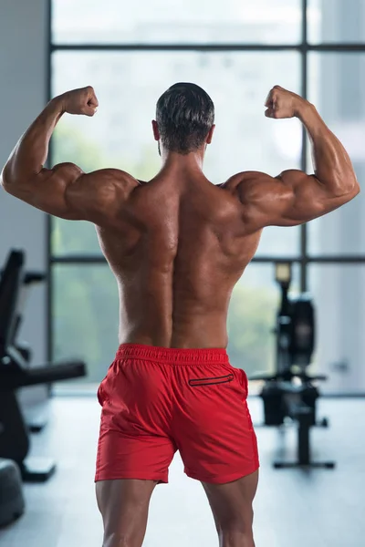 Junge Bodybuilderin biegt hinteren doppelten Bizeps — Stockfoto