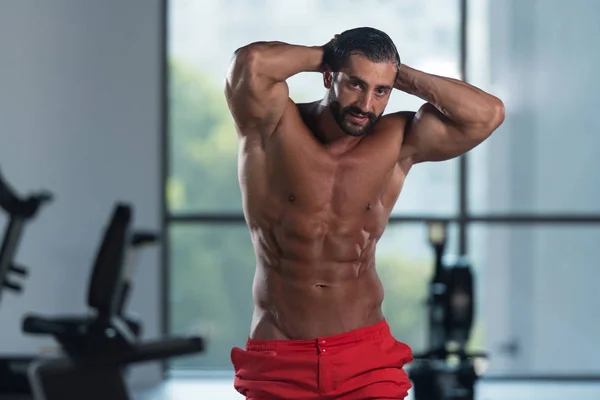 Gespierde man buigen spieren in de sportschool — Stockfoto