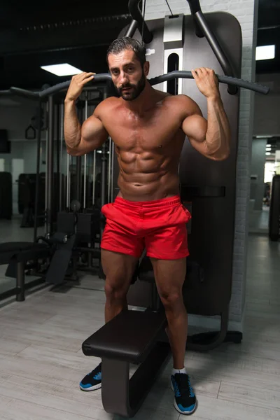 Kraftvoller muskulöser Mann trainiert Rücken an Seilmaschine — Stockfoto