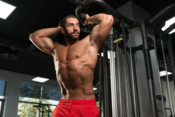 Bodybuilder faisant l'exercice pour des triceps avec le câble — Photo