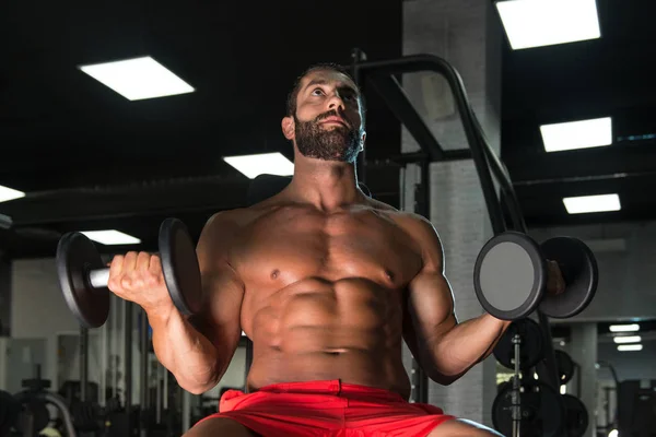 Homem muscular treinamento bíceps com halteres — Fotografia de Stock