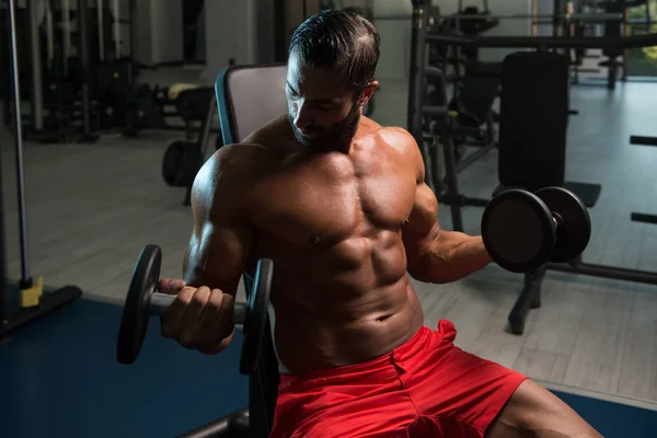 Muscular hombre entrenamiento bíceps con sombrillas — Foto de Stock