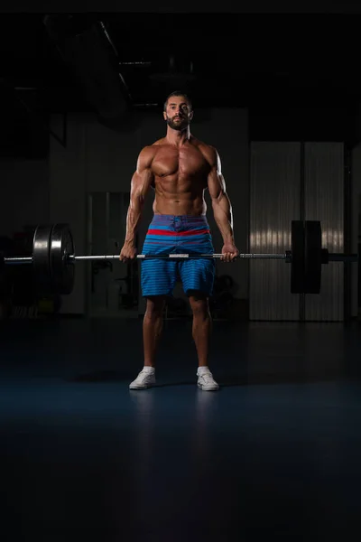 Hombre muscular haciendo ejercicio de nuevo con la barra en el gimnasio —  Fotos de Stock