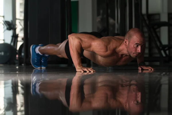 Jeune bodybuilder exerçant des redressements de presse sur le plancher — Photo