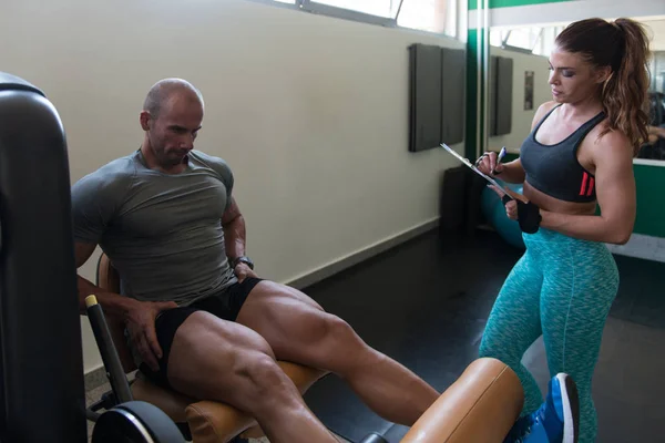 Man trein benen op Machine met Personal Trainer — Stockfoto