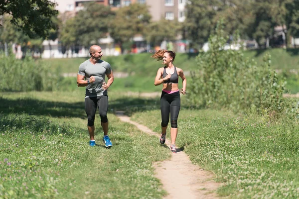 Pareja joven corriendo al aire libre en un día encantador — Foto de Stock