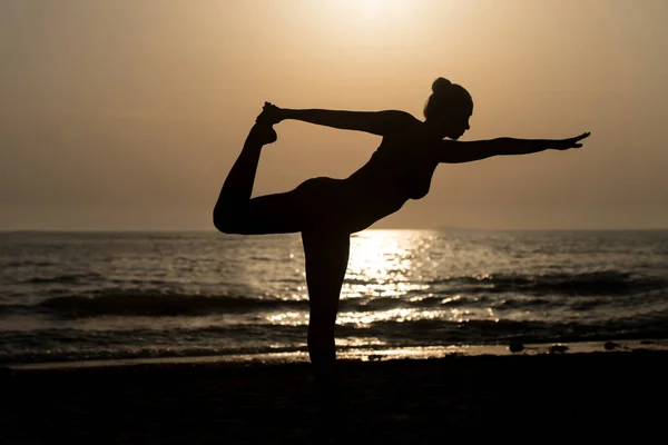 Mujer joven practicando yoga en la playa — Foto de Stock