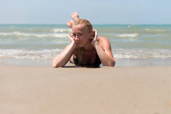 Mulher deitada na areia da costa oceânica — Fotografia de Stock