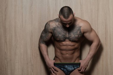 Ahşap arka plan üzerinde izole seksi dövme adam