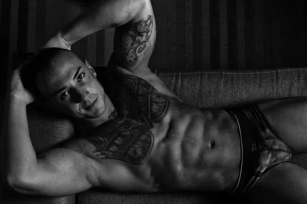 ソファに横たわる強い上半身裸の若い男 — ストック写真