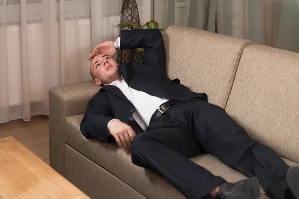 Joven hombre de negocios durmiendo en el sofá en casa — Foto de Stock