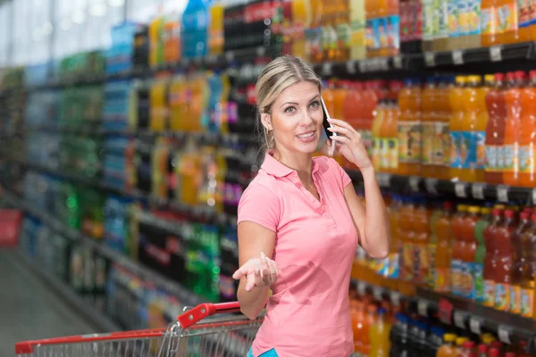 Femme avec téléphone portable dans un supermarché — Photo