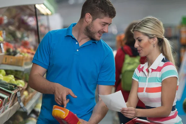 Par med indkøbsliste i supermarkedet - Stock-foto