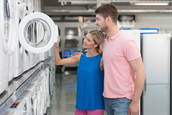 Sorrindo casal compra máquina de lavar roupa no supermercado — Fotografia de Stock