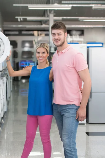 Belle jeune couple faisant du shopping machine à laver dans le supermarché — Photo