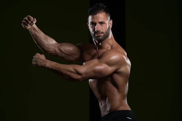 Musculoso hombre flexionando los músculos en el gimnasio — Foto de Stock