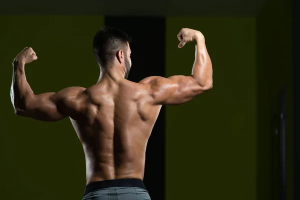Uomo muscolare che flette i muscoli in palestra — Foto Stock