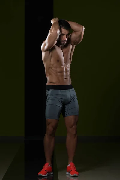 Svalnatý muž protahuje svaly v posilovně — Stock fotografie