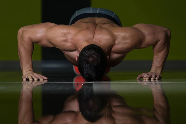 Homem muscular realizando empurrar Ups no chão — Fotografia de Stock