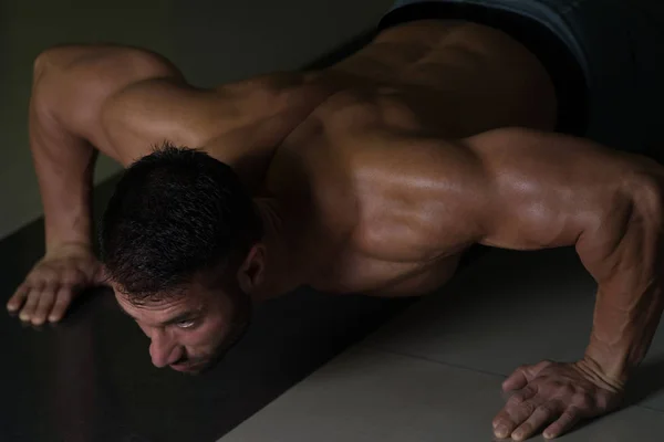 Uomo muscolare che esegue spingere Ups sul pavimento — Foto Stock