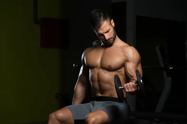 Hombre muscular ejercitando bíceps con mancuerna —  Fotos de Stock