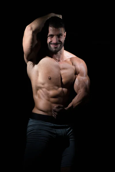 Musculoso hombre flexionando los músculos en el gimnasio — Foto de Stock