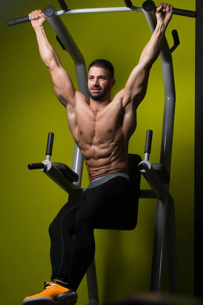 Homem muscular executando pendurado perna levanta exercício — Fotografia de Stock