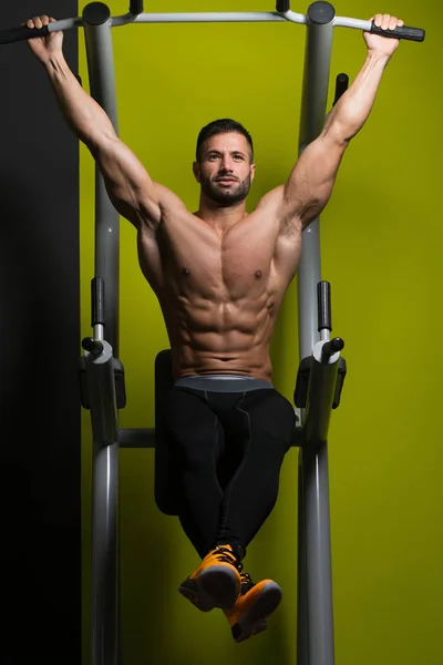 Homem muscular executando pendurado perna levanta exercício — Fotografia de Stock