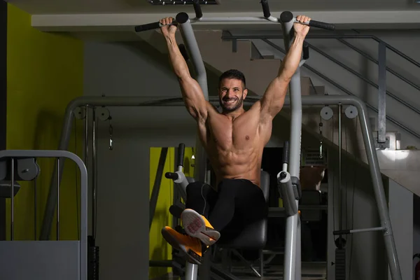 Hombre sano realizando la pierna colgante eleva el ejercicio — Foto de Stock