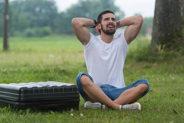 Gefrustreerde Man zit op gras met Case Drone — Stockfoto