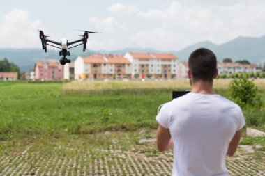 Adam açık havada uçan bir dron uzaktan kumanda ile