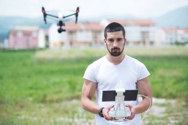 Adam açık havada uçan bir dron uzaktan kumanda ile