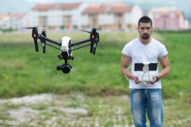 Adam açık havada uçan bir dron uzaktan kumanda ile