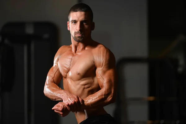 Gespierde man buigen spieren in de sportschool — Stockfoto