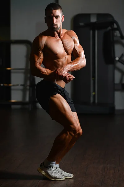 Grave joven culturista de pie en el gimnasio — Foto de Stock