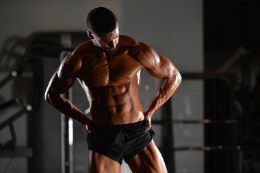 Spor salonunda ayakta ciddi genç vücut geliştirmeci