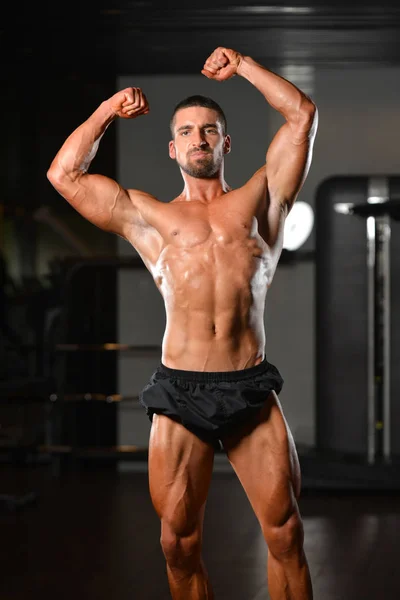 Grave joven culturista de pie en el gimnasio — Foto de Stock