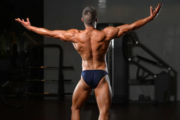 Svalnatý muž protahuje svaly v posilovně — Stock fotografie
