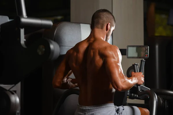 Young Man Doing Back Exercise On A Machine — Stock Photo, Image