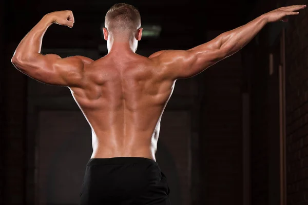 Musculoso hombre flexionando los músculos en el gimnasio — Foto de Stock