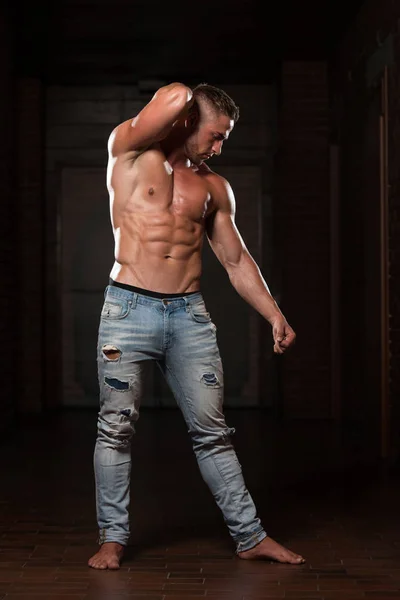 Молодой человек в джинсах демонстрирует мышцы — стоковое фото