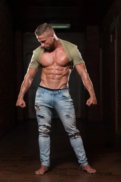 Junger Mann in Jeans lässt Muskeln spielen — Stockfoto