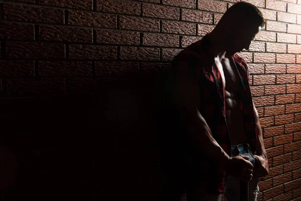 Hombre flexionando músculos en la pared de ladrillos — Foto de Stock