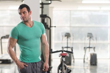 Yeşil T-shirt arka plan spor salonunda güçlü adam