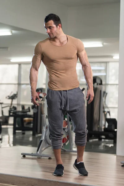 Silný muž v tělocvičně pozadí hnědé tričko — Stock fotografie