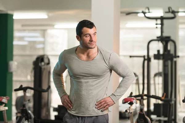 Hombre fuerte en camiseta verde fondo gimnasio —  Fotos de Stock