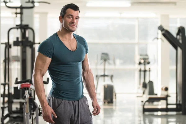 Hombre fuerte en camiseta verde fondo gimnasio —  Fotos de Stock