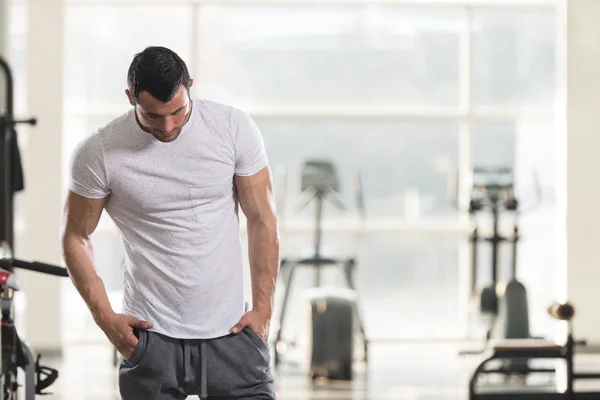 Uomo forte in bianco T-shirt sfondo Palestra — Foto Stock