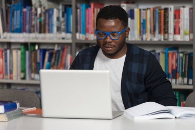 Diz üstü bir kütüphaneyi kullanan genç öğrenci