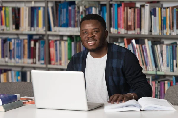 Heureux étudiant africain masculin avec ordinateur portable dans la bibliothèque — Photo
